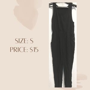 Black romper with pockets and buttons on the side.